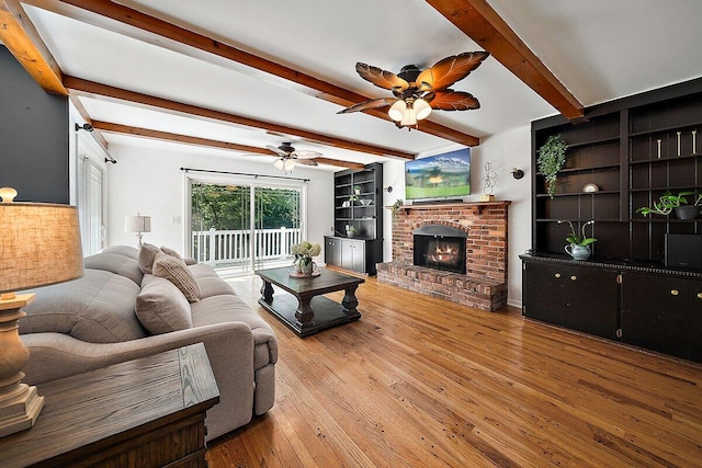 4550 Comanche Dr, Okemos, MI 48864 - living room with a ceiling fan, beamed ceiling, hardwood / wood-style floors, and a brick fireplace