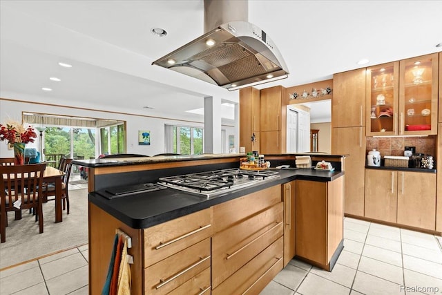 1540 Milford Hills Dr, Milford, MI 48381 - kitchen featuring stainless steel gas cooktop, island exhaust hood, light tile patterned floors, dark countertops, and healthy amount of natural light