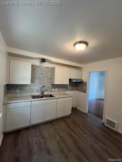 15475 Prest St, Detroit, MI 48227 - kitchen featuring white cabinetry, backsplash, light countertops, dark wood finished floors, and ventilation hood