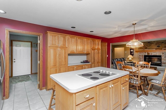 5237 Emerson Dr, Ottawa Lake, MI 49267 - kitchen with white electric stovetop, light countertops, a center island, light tile patterned floors, and a fireplace