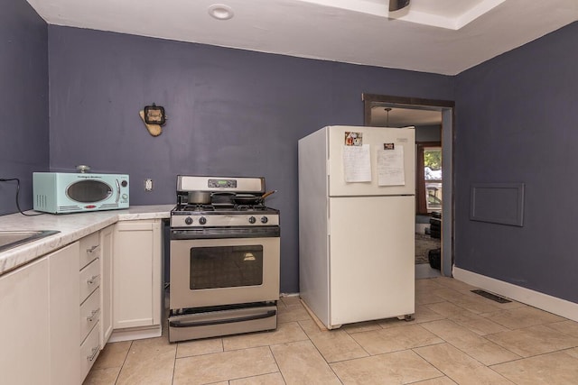 1228 Wells Pl, Kalamazoo, MI 49001 - kitchen featuring freestanding refrigerator, gas range, light countertops, white cabinets, and light tile patterned floors