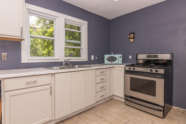 1228 Wells Pl, Kalamazoo, MI 49001 - kitchen with stainless steel gas range oven, light countertops, light tile patterned flooring, and white cabinetry