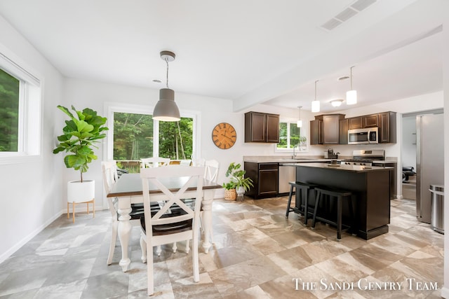 568 N River Hills Dr, Newaygo, MI 49337 - kitchen featuring appliances with stainless steel finishes, dark brown cabinets, a kitchen island, and a kitchen breakfast bar