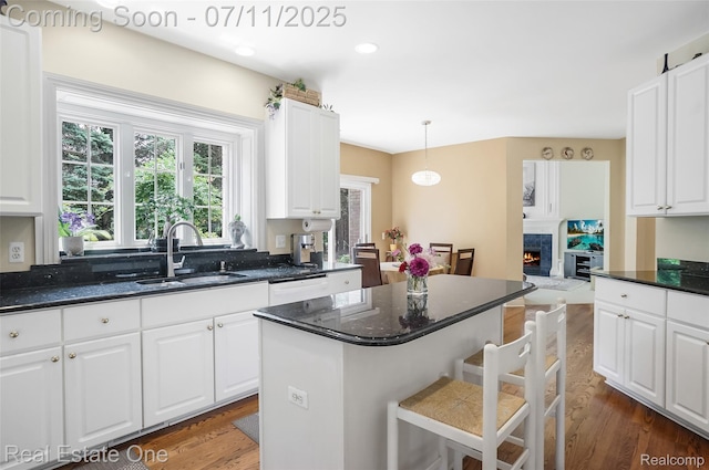 3565 Heron Ridge Dr, Rochester Hills, MI 48309 - kitchen with a kitchen bar, white cabinetry, dark wood finished floors, a lit fireplace, and dark stone counters