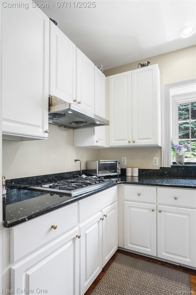 3565 Heron Ridge Dr, Rochester Hills, MI 48309 - kitchen featuring under cabinet range hood, white cabinetry, dark stone counters, stainless steel gas cooktop, and dark wood finished floors