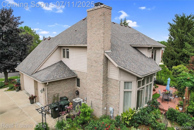 3565 Heron Ridge Dr, Rochester Hills, MI 48309 - view of home's exterior with a chimney, a wooden deck, a shingled roof, outdoor dining space, and driveway