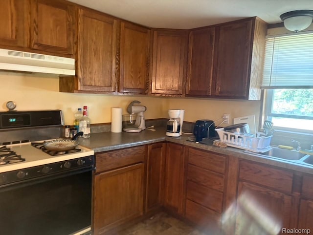 1023 Lakewood Dr, East Tawas, MI 48730 - kitchen with black range with gas cooktop, under cabinet range hood, and brown cabinetry