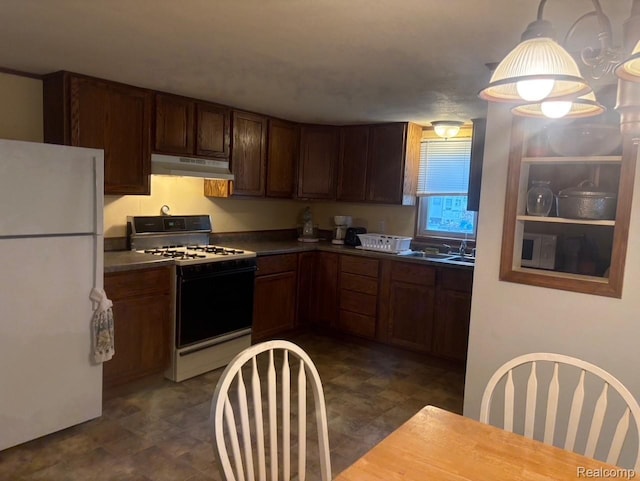 1023 Lakewood Dr, East Tawas, MI 48730 - kitchen with freestanding refrigerator, gas range, under cabinet range hood, dark countertops, and pendant lighting