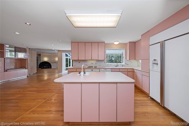 4724 Tara Ct, West Bloomfield, MI 48323 - kitchen featuring paneled built in fridge, light countertops, light wood-type flooring, backsplash, and a kitchen island with sink