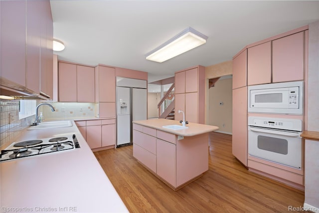4724 Tara Ct, West Bloomfield, MI 48323 - kitchen with built in appliances, light countertops, light wood-style floors, backsplash, and a center island with sink