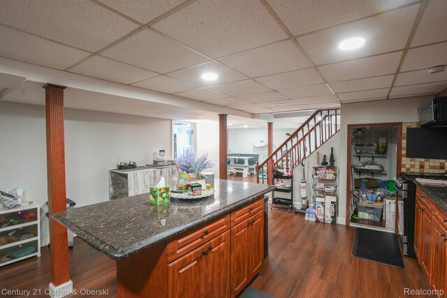 5720 Argyle St, Dearborn, MI 48126 - kitchen with gas range, dark wood-style flooring, dark stone counters, brown cabinets, and a kitchen island