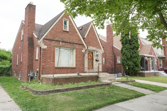 5720 Argyle St, Dearborn, MI 48126 - tudor-style house featuring a chimney, brick siding, and roof with shingles