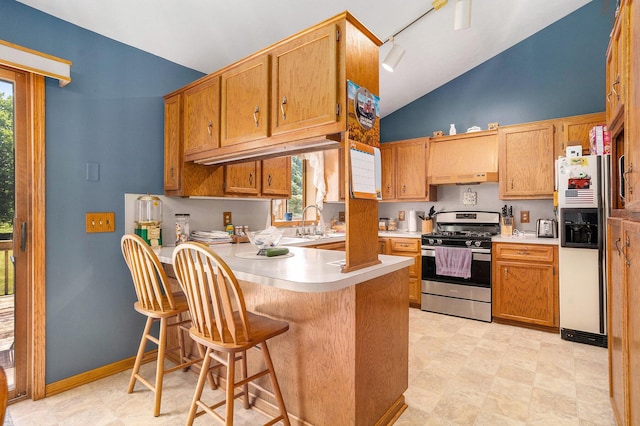 6580 Sunflower Dr SW, Byron Center, MI 49315 - kitchen featuring gas range, white fridge with ice dispenser, a peninsula, light countertops, and high vaulted ceiling