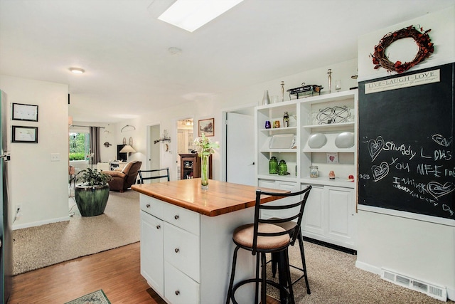 12972 S M 43 Hwy, Delton, MI 49046 - kitchen with butcher block countertops, white cabinetry, a kitchen bar, a kitchen island, and open floor plan