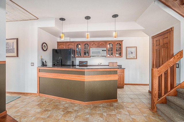 481 Seminole Rd, Norton Shores, MI 49444 - kitchen featuring black fridge, white microwave, dark countertops, glass insert cabinets, and hanging light fixtures