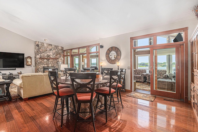 481 Seminole Rd, Norton Shores, MI 49444 - dining space with lofted ceiling, dark wood-type flooring, and a fireplace