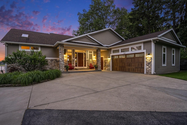 481 Seminole Rd, Norton Shores, MI 49444 - view of front of home with stone siding, covered porch, a garage, and driveway