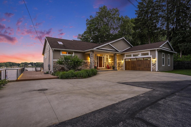 481 Seminole Rd, Norton Shores, MI 49444 - view of front of home featuring stone siding, concrete driveway, an attached garage, and covered porch