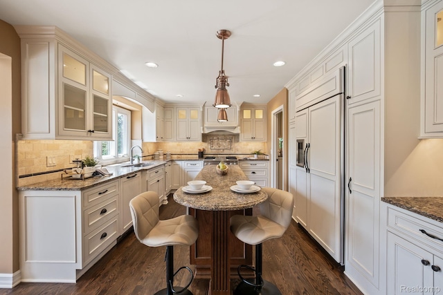1257 Lake Shore Blvd, Lake Orion, MI 48362 - kitchen with dark wood-style floors, a kitchen island, paneled built in fridge, glass insert cabinets, and dark stone counters