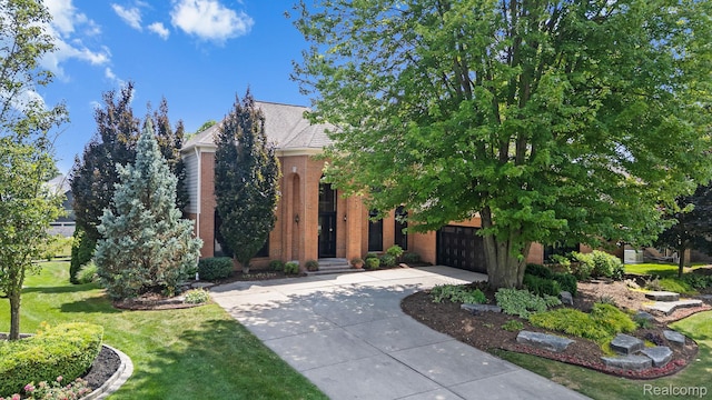1257 Lake Shore Blvd, Lake Orion, MI 48362 - obstructed view of property featuring concrete driveway, an attached garage, brick siding, and a front yard