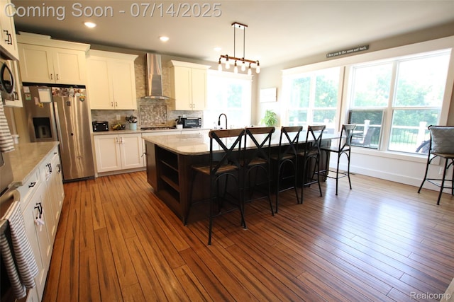 4385 Nelson Scott Dr, Holly, MI 48442 - kitchen with wall chimney exhaust hood, stainless steel refrigerator with ice dispenser, a breakfast bar area, decorative backsplash, and recessed lighting