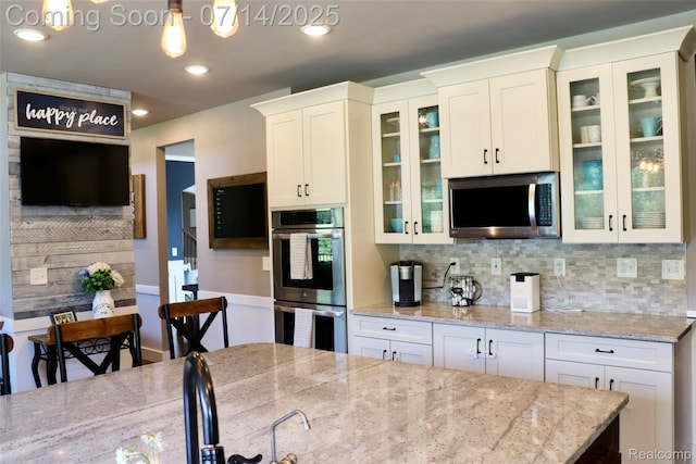 4385 Nelson Scott Dr, Holly, MI 48442 - kitchen featuring stainless steel appliances, decorative backsplash, white cabinets, light stone countertops, and glass insert cabinets