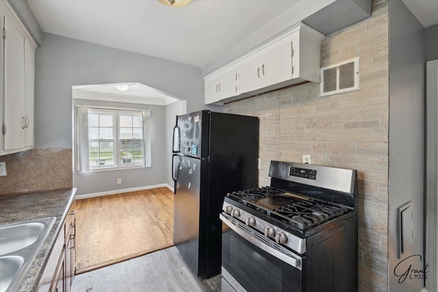 19007 Kentfield St, Detroit, MI 48219 - kitchen featuring stainless steel gas stove, freestanding refrigerator, white cabinets, light wood finished floors, and tasteful backsplash