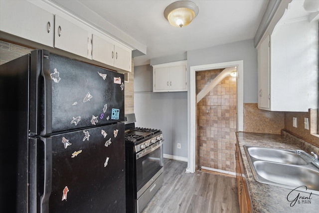 19007 Kentfield St, Detroit, MI 48219 - kitchen featuring freestanding refrigerator, stainless steel gas stove, white cabinetry, light wood-style flooring, and decorative backsplash