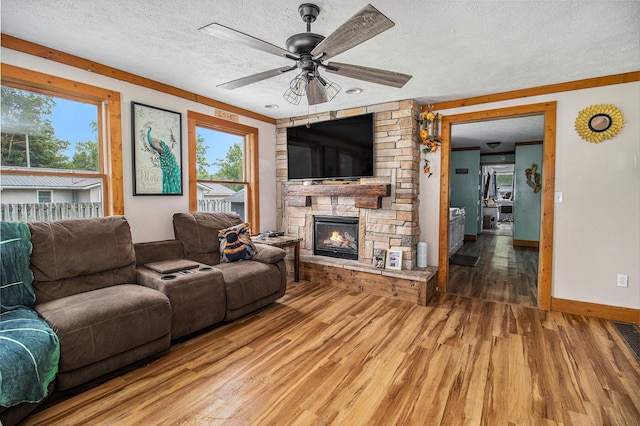 515 Locust St, Howard City, MI 49329 - living room featuring wood finished floors, a textured ceiling, a stone fireplace, and a ceiling fan