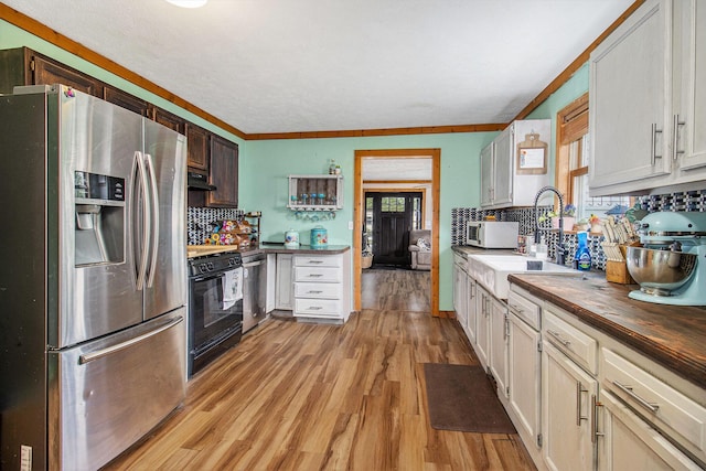 515 Locust St, Howard City, MI 49329 - kitchen with appliances with stainless steel finishes, light wood-style flooring, decorative backsplash, under cabinet range hood, and butcher block countertops