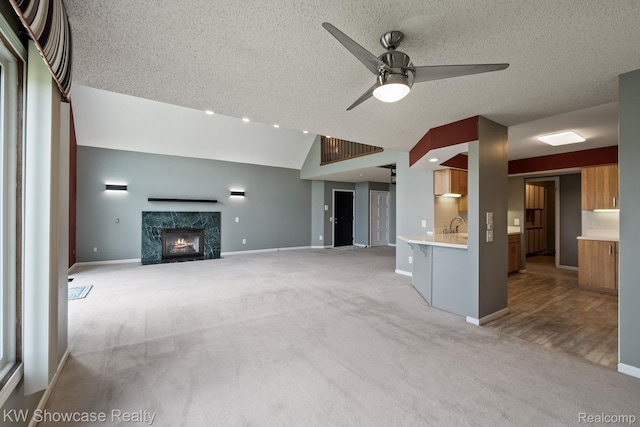 3410 Adams Shore Dr, Waterford, MI 48329 - unfurnished living room featuring light colored carpet, vaulted ceiling, a ceiling fan, a premium fireplace, and a textured ceiling