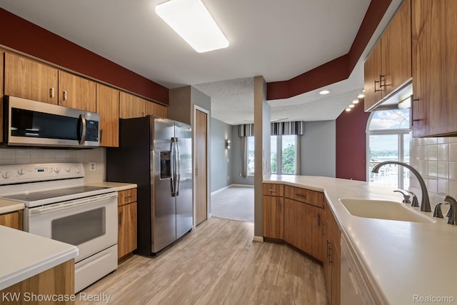 3410 Adams Shore Dr, Waterford, MI 48329 - kitchen with stainless steel appliances, backsplash, brown cabinetry, light wood-style flooring, and light countertops