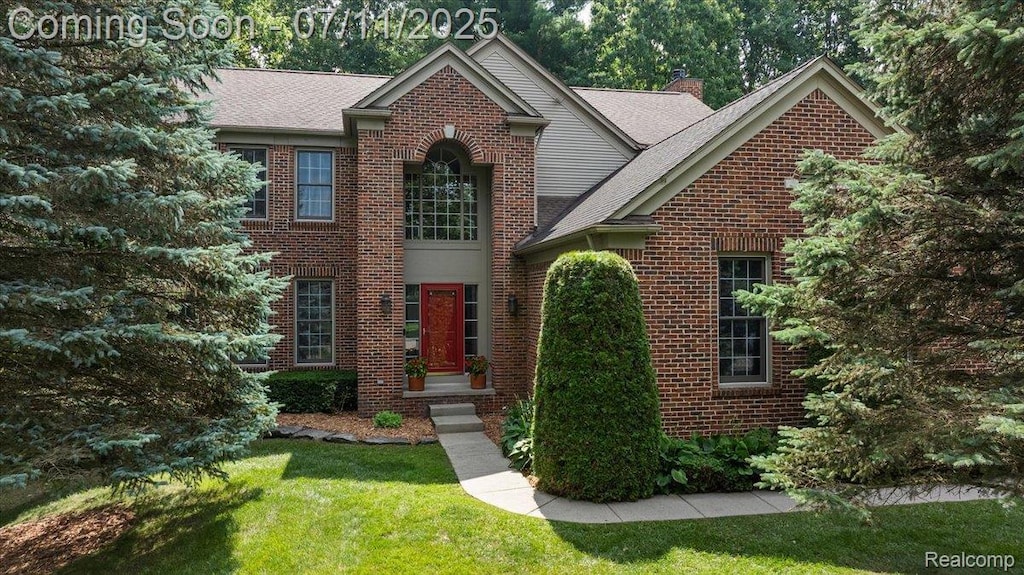 3606 Seney Dr, Lake Orion, MI 48360 - view of front of house featuring brick siding, a front yard, a chimney, and a shingled roof