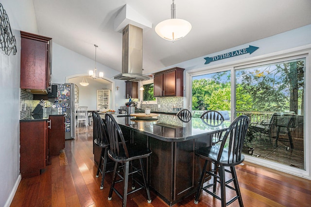191 S Lake Doster Dr, Plainwell, MI 49080 - kitchen featuring island range hood, vaulted ceiling, tasteful backsplash, dark wood-style flooring, and a breakfast bar