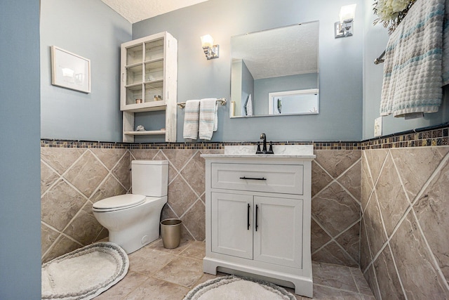 191 S Lake Doster Dr, Plainwell, MI 49080 - bathroom featuring tile walls, vanity, wainscoting, and a textured ceiling