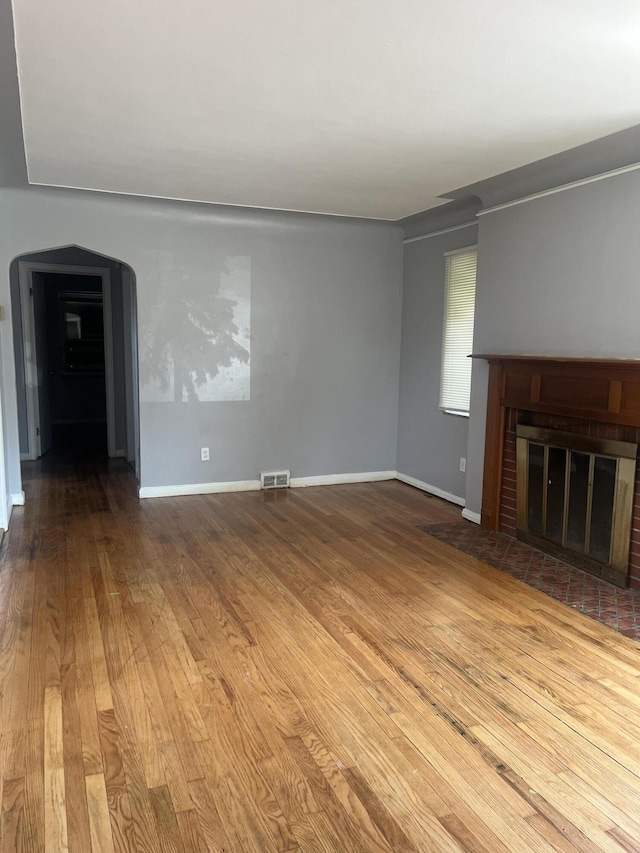 16609 Edmore Dr, Detroit, MI 48205 - unfurnished living room with wood finished floors, a brick fireplace, and arched walkways