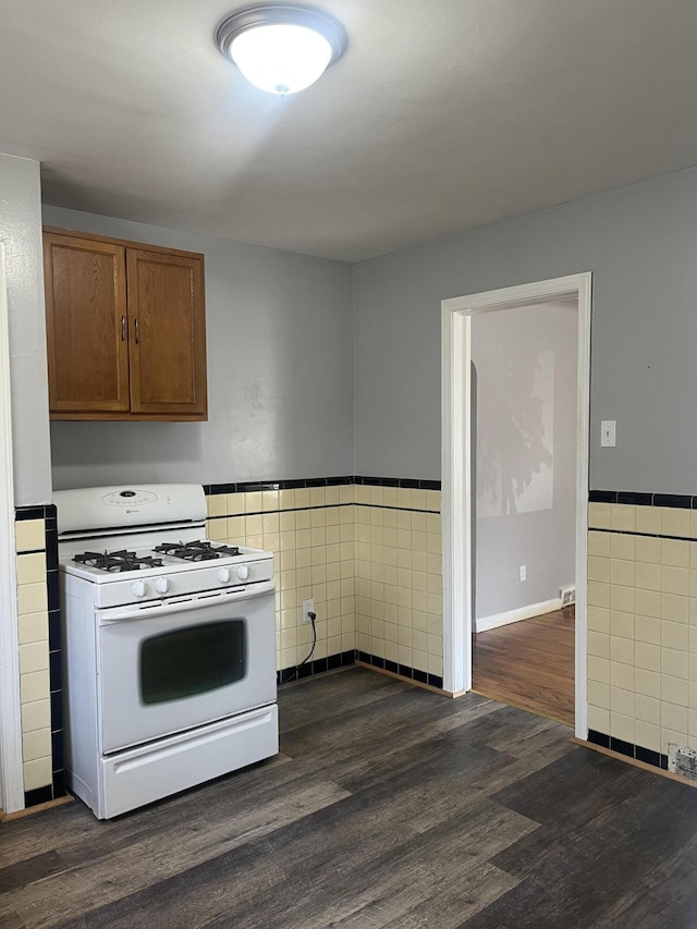 16609 Edmore Dr, Detroit, MI 48205 - kitchen with white gas stove, tile walls, dark wood-style flooring, wainscoting, and brown cabinets