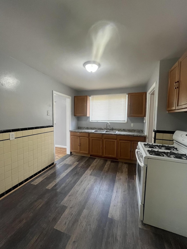 16609 Edmore Dr, Detroit, MI 48205 - kitchen featuring white gas range, brown cabinetry, dark wood-style floors, wainscoting, and tile walls