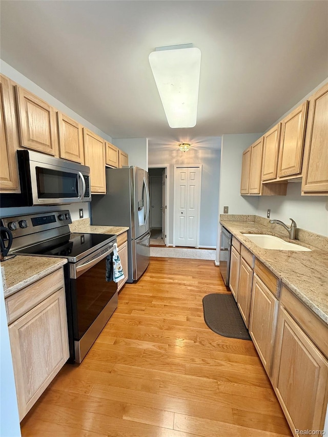 6426 Club Ct W, Grand Blanc, MI 48439 - kitchen with stainless steel appliances, light brown cabinetry, light wood-style floors, and light stone countertops