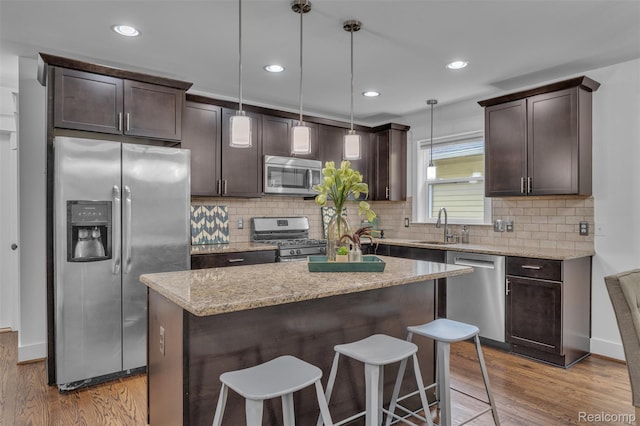 715 Gardenia Ave, Royal Oak, MI 48067 - kitchen featuring stainless steel appliances, dark brown cabinets, wood finished floors, a breakfast bar area, and recessed lighting