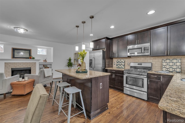 715 Gardenia Ave, Royal Oak, MI 48067 - kitchen with appliances with stainless steel finishes, a breakfast bar area, dark brown cabinetry, light stone counters, and recessed lighting