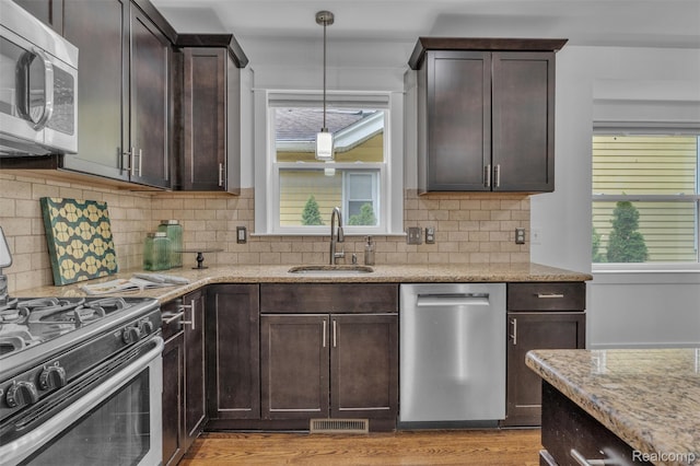 715 Gardenia Ave, Royal Oak, MI 48067 - kitchen with appliances with stainless steel finishes, light stone counters, dark brown cabinets, and plenty of natural light