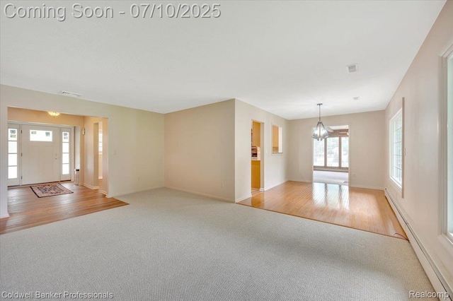 1526 Rulane Dr, Lapeer, MI 48446 - unfurnished living room featuring carpet flooring, a chandelier, a baseboard heating unit, and wood finished floors