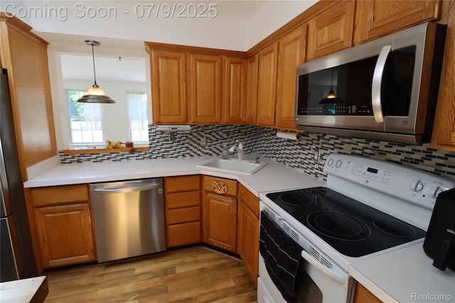 9360 Gale Rd, Goodrich, MI 48438 - kitchen featuring stainless steel appliances, light wood finished floors, tasteful backsplash, hanging light fixtures, and brown cabinets