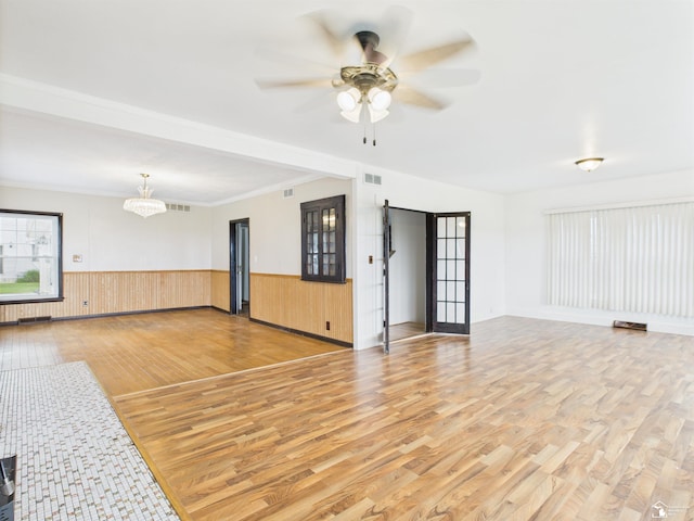4356 14th St, Luna Pier, MI 48157 - unfurnished living room with light wood-style floors, a ceiling fan, a wainscoted wall, and a chandelier