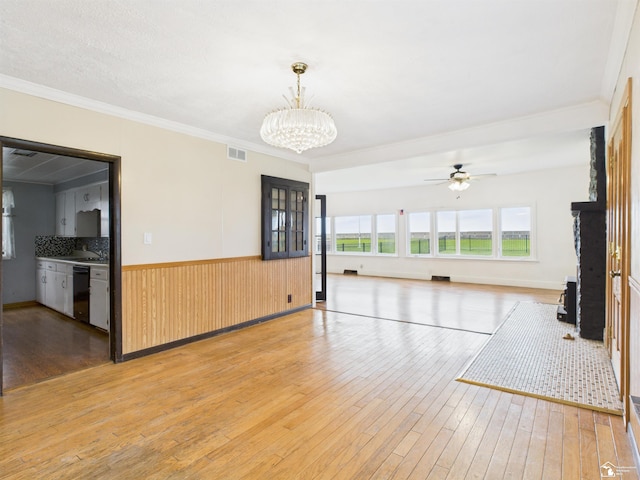 4356 14th St, Luna Pier, MI 48157 - unfurnished living room with light wood-style floors, crown molding, a chandelier, a ceiling fan, and wainscoting