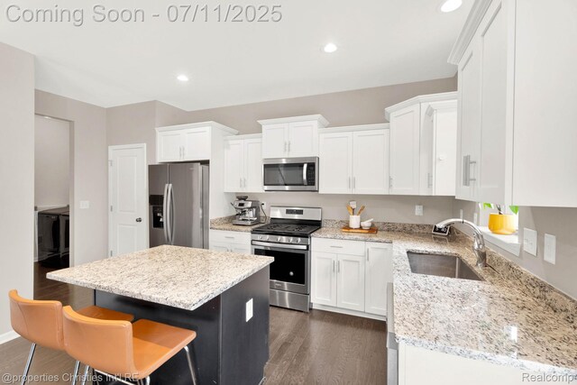 2962 Iowa Dr, Troy, MI 48083 - kitchen featuring stainless steel appliances, white cabinets, dark wood-style floors, a center island, and a breakfast bar area