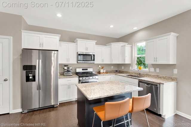 2962 Iowa Dr, Troy, MI 48083 - kitchen featuring appliances with stainless steel finishes, white cabinetry, a center island, dark wood-type flooring, and light stone counters