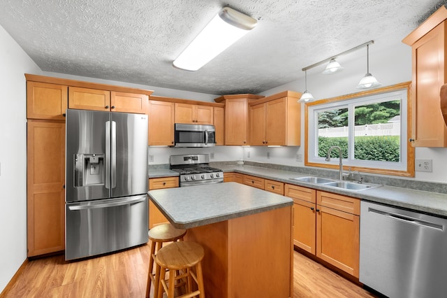 22100 N Uldriks Dr, Battle Creek, MI 49017 - kitchen with stainless steel appliances, light wood-type flooring, a textured ceiling, a center island, and a kitchen breakfast bar