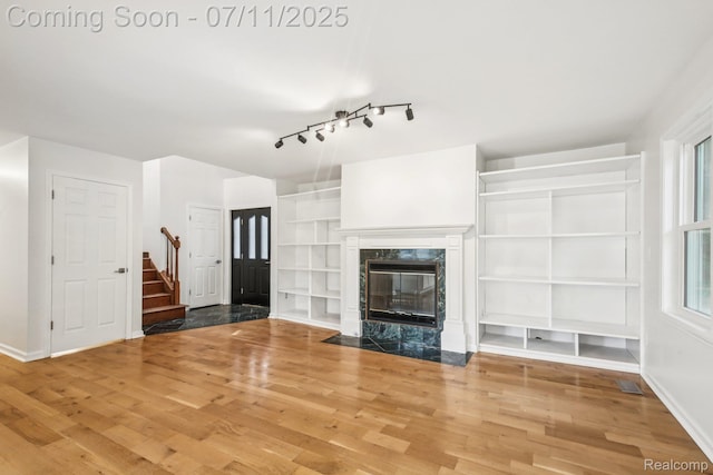 10746 Winthrop, Pinckney, MI 48169 - unfurnished living room with stairway, wood finished floors, rail lighting, and a high end fireplace
